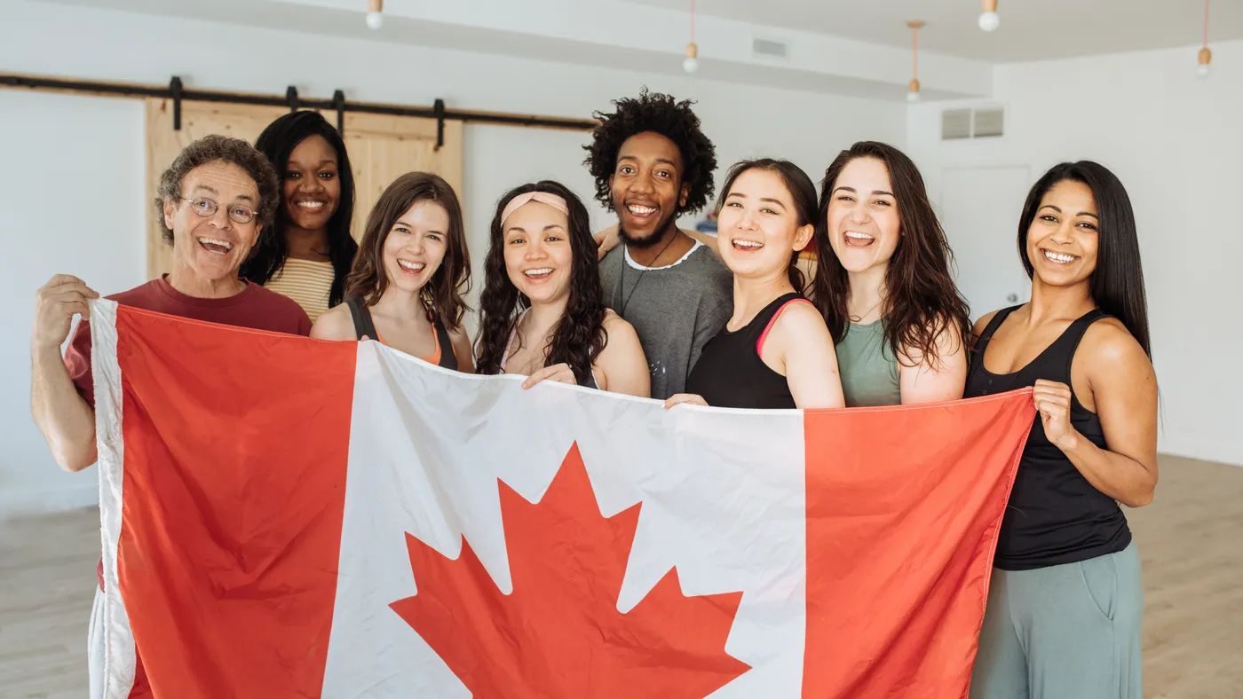Groupe d'amis souriants tenant un drapeau du Canada